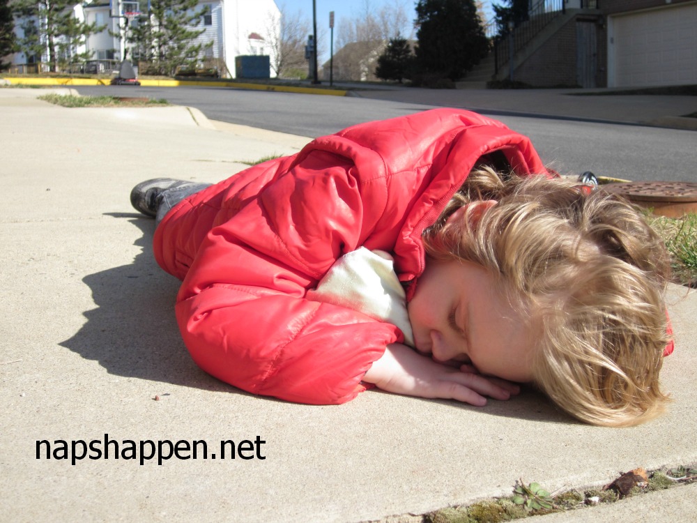 child asleep on sidewalk